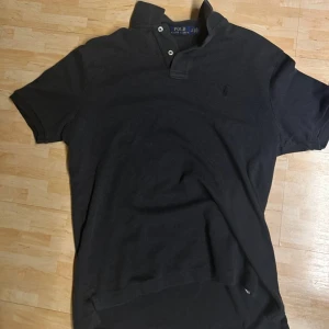 Svart kortärmad skjorta Polo Ralph Lauren - Svart kortärmad skjorta från Polo Ralph Lauren med klassisk krage och två knappar vid halsen. Skjortan har en diskret broderad logga på bröstet och är tillverkad i mjuk bomull. Perfekt för en clean och stilren look. Nypris ca 1800kr mitt pris 600kr❗️❗️ Priset är inte fast så skicka gärna prisförslag och hör gärna av er vid funderingar🙌🏼