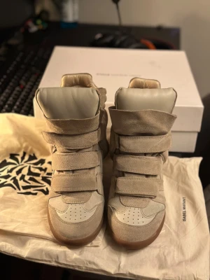 Beige Isabel Marant skor - Säljer mina fina Isabelle Marant skor som bara använts nagra få gänger. De är i perfekt skick, utan minsta repa eller fläck, och känns nästan som nya. Originalbox och två dust bags följer med, sa allt är redo för nästa ägare.❤️🩷 Det här är verkligen en perfekt liten lyxpresent att lägga under granen🎄🎁