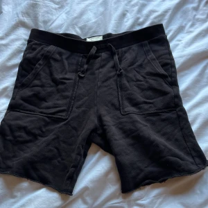 Svarta shorts från Zadig & Voltaire - Svarta shorts från Zadig & Voltaire med bred resår i midjan och snörning framtill. De har två stora fickor fram och en bakficka med coolt tryck. Materialet är mjukt och känns som bomull, perfekt för chill dagar. Rå kant nedtill ger en avslappnad vibe.