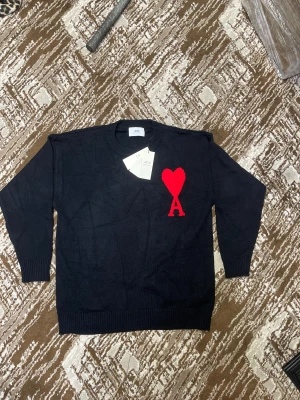 Svart stickad tröja från Ami - Svart stickad tröja från med rund hals och ribbade muttrar. Perfekt för dig som gillar stilrena plagg med en twist.