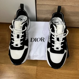 Dior B25 sneakers svart/vit - Säljer ett par Dior B25 sneakers i svart och vitt med klassisk Dior-logga på sidan. Skorna har en chunky sula, mesh och mockadetaljer samt vita snören. Snygg kontrast mellan svart mocka och vit mesh, samt diskret Dior-mönster på sidan. Perfekta för dig som gillar lyxiga statement-sneakers. Vid snabb affär kan priset ner direkt.