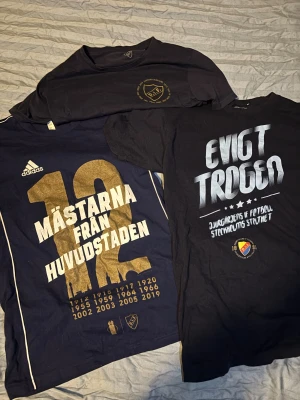Djurgården t-shirt paket - Tre snygga Djurgården t-shirts i svart och mörkblå med tryck som 'Evigt trogen' och 'Mästarna från huvudstaden'. En av tröjorna är från Adidas med guldtryck och årtal, perfekt för dig som älskar fotboll och vill visa ditt stöd för Stockholms stolthet. 2 av dom är i S och 1 är M