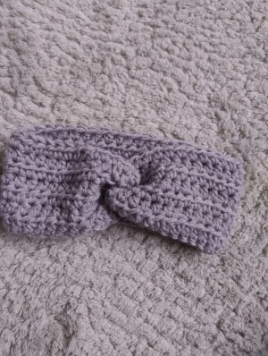 Handgjort virkat pannband grå - Supermysigt virkat pannband i ljusgrå som jag gjort själv. Bred modell med twistad knut framtill som ger en snygg detalj. Passar dig som vill ha både värme och stil på vintern.