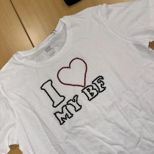 Vit t-shirt I❤️My bf  - Vit t-shirt från 157 med coolt print 'I ♥ MY BF' på bröstet, där bokstäverna och hjärtat är dekorerade med svarta och röda pärlor. Tröjan är i grund från lager 157, går att tvätta OBS! Bara i 30 grader och ingen torktumling 