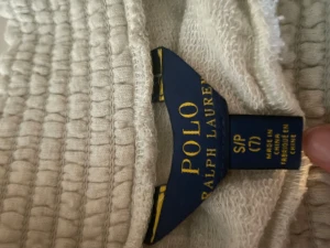 Beige volangkjol från Polo Ralph Lauren - Supersöt beige kortkjol från Polo Ralph Lauren med bred, ribbad resår i midjan och flera lager volanger. Kjolen är gjord i mjuk bomull och har en luftig och chill vibe, perfekt för att styla med sneakers eller boots. Volangdetaljerna ger extra rörelse och en trendig look.