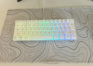  61 Key RGB Gaming Keyboard -  61-tangenters RGB gaming-tangentbord med USB-anslutning. Snygg vit design med färgglad bakgrundsbelysning. Modell G70, i mycket gott skick utan synligt slitage. Perfekt för gaming och skrivbord med begränsat utrymme.