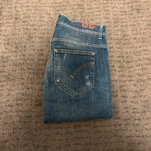 Dondup Jeans - Snygga blå jeans från Dondup i slim fit-modell med klassisk femficksdesign. Jeansen har slitna detaljer och kontrastsömmar på bakfickorna. Passformen är smal och materialet är mjukt denim för en bekväm känsla. Perfekt för dig som gillar en modern och stilren look.