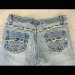 Vintage lågmidjade bootcut jeans med detalj på fickor - Ursnygga low waist jeans med guldiga spets detaljer på baksidan!! Hade passat dig som är lite kortare  i strl xs-s, exakta midjemått är 36 och innerbenslängd 76. Vissa diamant paljetter har tyvärr ramlat av. Det är bara att kontakta mig vid frågor🥰