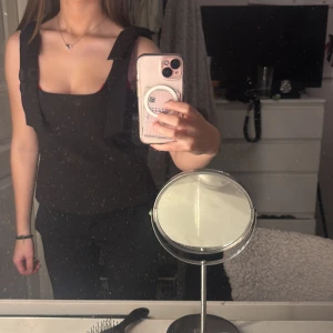 Svart linnetopp med breda axelband från Zara - Hej säljer en fin fest linnetopp från Zara i färgen svart med breda axelband med rosetter vid axlarna och fyrkantig urringning. Tröjan är super fint skick aldrig använd på den inte faller mig i smaken. Den är i XS men passar även S