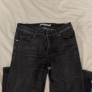 Svarta bootcut jeans från Marie Alexander - Snygga svarta jeans från Marie Alexander med klassisk femficksdesign och bootcut-ben. Jeansen har en mörk tvätt och subtila slitningar för en cool look. Passar dig som gillar lite vidare ben och stilren design. Materialet är jeans med stretch för extra komfort. Low waist! 