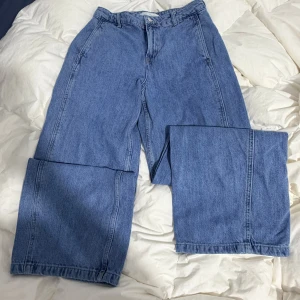 Wide jeans från Zara i ljusblå denim - Säljer ett par ljusblå jeans från Zara med breda ben och klassisk femficksdesign. Byxorna har hög midja, raka sömmar och är tillverkade i mjuk denim. Perfekt för dig som gillar en loose och avslappnad stil.
