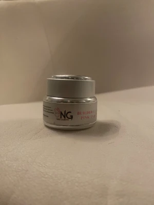 NG Builder Gel Pink 15 gr - NG Builder Gel Pink 15 gr i en rund, silvrig burk. Gelen har en ljusrosa ton och används för att bygga och förstärka naglar. Perfekt för dig som gillar att fixa naglarna hemma och vill ha en naturlig, fräsch look. Umgefär hälften kvar