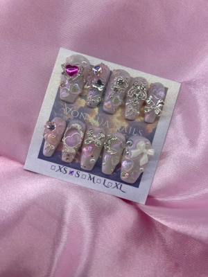 Hime (S);Medium Coffin - Handgjorda press-on naglar i ljusrosa med rosa pärlemorskimmer, dekorerade med silverdetaljer, pärlor, rosetter och hjärtan. Setet har 3D-element som metallrosetter, lila och rosa stenar samt vita och silverfärgade dekorationer. Perfekt för dig som vill ha extra glam och unik design.S: 15 mm, 11,5 mm, 12 mm, 11 mm, 9 mm 
