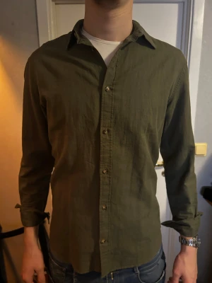 Olivgrön skjorta med knappar - Schysst olivgrön skjorta ifån jack and jones. Strlk S. Modellen är 193 och väger 82kg. Köpt för 600. Pris kan diskuteras