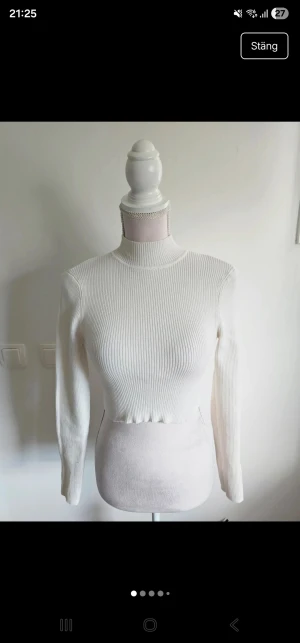 Vit croppad polotopp från H&M Divided - Säljer en vit croppad polotopp från H&M Divided i storlek S. Toppen är ribbad med lång ärm och har en hög krage som ger en clean och modern vibe. Materialet är mjukt och stretchigt, perfekt för att styla med jeans eller kjol. Enkel att matcha och superfräsch!