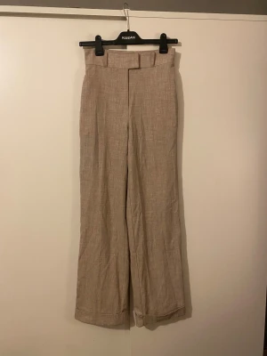 Beige linnebyxor från NA-KD, storlek 34 - Liknar linnebyxor, från NA-KD i storlek 34. Hög midja, raka ben och knytband i midjan. Upplever dem lite stora i storleken