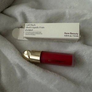 Rare Beauty Soft Pinch Liquid Blush - Rare Beauty Soft Pinch Liquid Blush i färgen Grateful. Flytande rouge med intensiv röd nyans, kommer i en frostad glasflaska med lyxigt guldfärgat lock. Perfekt för att ge kinderna en fräsch och pigg look. Volym: 7,5 ml.