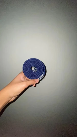 Mörkblå flätad tygbälte - Snyggt mörkblått bälte i flätad design med silverfärgat spänne. Bältet är gjort av ett slitstarkt tygmaterial och har en enkel, stilren look som passar till jeans eller chinos. Perfekt för dig som vill ha en clean accessoar med lite struktur. 110cm