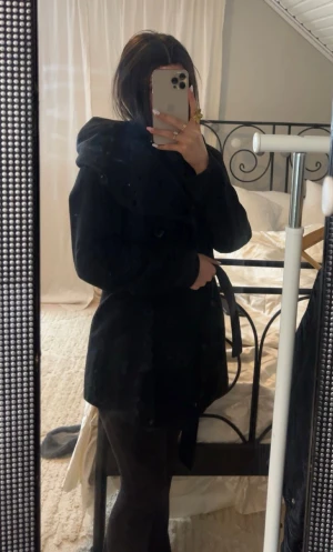 Svart kappa med bälte och stora slag - Svart kappa med stora slag, knappar framtill och bälte i midjan. Klassisk och stilren modell med lång ärm och rak passform. Perfekt för dig som gillar en clean och tidlös look.