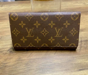 Hand väska  - En klassiskt monogrammönster i guld. Plånboken är tillverkad i skinn och har flera fack för kort och sedlar, Perfekt storlek för att ha med sig överallt.