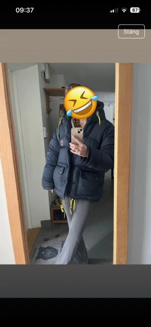 Mörkblå pufferjacka från Fjällräven XXS - Säljer en mörkblå pufferjacka från Fjällräven i storlek XXS. Jackan har huva, gula snören och två stora fickor med knappar framtill. Perfekt för kalla dagar och har en cool, oversized vibe. Materialet är syntet och dun, med dragkedja och knappar framtill.