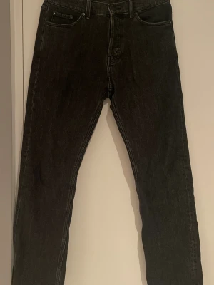 Svarta raka jeans från Weekday - Svarta jeans från Weekday med rak passform och klassisk femficksdesign. Jeansen har hög midja och är tillverkade i slitstarkt bomullsmaterial. Modellen är space (lite bredare)