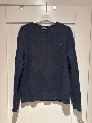 Marinblå kabelstickad tröja GANT, storlek M - Marinblå kabelstickad tröja från GANT i storlek M. Tröjan är i mycket bra skick.
