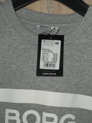 Grå sweatshirt från Björn Borg - Snygg ljusgrå sweatshirt från Björn Borg med vitt tryck framtill. Tröjan har rund halsringning och långa ärmar. Tillverkad i mjukt material som passar perfekt för en avslappnad stil. Klassisk och enkel design med tydlig logga.