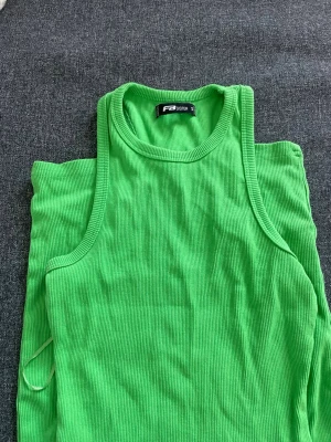 Grön ribbad ärmlös klänning B.Young - Säljer en snygg grön ribbad klänning från B.Young. Klänningen är ärmlös med rund halsringning och har en kroppsnära passform. Perfekt för sommarens alla tillfällen och enkel att styla med sneakers eller sandaler.