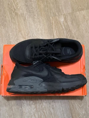 Svarta Nike Air Max sneakers - Säljer ett par helsvarta Nike Air Max sneakers med klassisk rund tå och snörning. Skorna har en synlig Air Max-sula och är tillverkade i en mix av syntet och mesh för bra komfort och stilren look.