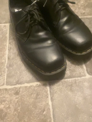 Dr martens - Dr. Martens 1461 bex squared i äkta skinn med snörning och robust sula. Modellen har en fyrkantig tå och den ikoniska gula sömmen runt sulan. 