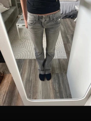 Grå jeans från Gina Tricot - Snygga grå jeans från Gina Tricot med klassisk femficksmodell och låg midja. Jeansen har raka ben och en tvättad look som ger en avslappnad vibe. Perfekta till vardags och lätta att matcha med olika stilar.