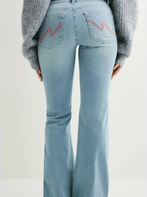 Ljusblå bootcut jeans med broderi - Snygga ljusblå jeans med bootcut passform och broderade detaljer i rosa på bakfickorna. Jeansen har låg midja och kommer från Nelly. Perfekta för dig som vill ha en retro och trendig look. Storlek 34. Bara defekter längst ner på jeansen