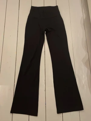 Svarta bootcut träningsbyxor  - Snygga svarta bootcut och utsvängda träningsbyxor som går att vika ned vid midjan. Vet ej varumärket men byxorna är köpta på Ullared. Storleken är ganska liten för att vara storlek 40.