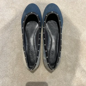 Diesel ballerinaskor i jeans med nitar - Snygga ballerinaskor från Diesel i blått jeanstyg med svarta skinnkanter och silverfärgade nitar runt öppningen. Aldrig använda så de är i helt nytt skick. De är i storlek 39 men passar även storlek 40.