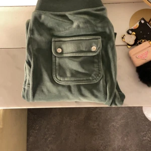 Gröna mjukisbyxor Juicy Couture M - ‼️‼️PRIS KAN SÄNKAS‼️‼️Mysiga gröna mjukisbyxor från Juicy Couture i storlek M. Byxorna har bred resår i midjan med snörning, stora fickor med lock och tryckknappar samt broderad logga på ena fickan. Mjukt material som känns lyxigt och skönt.