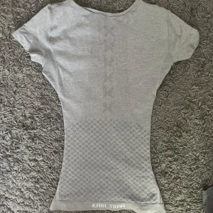 Grå träningstopp från Kari Traa - Superskön grå träningstopp från Kari Traa med diskret mönster och tight passform. T-shirten är kortärmad och har rund halsringning. Är insydd vid midjan