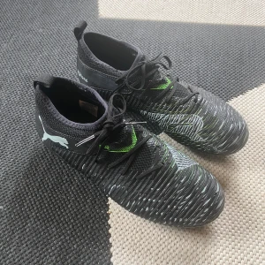 Puma future 8 match AG/FG Eclipse junior - Puma future 8 match FG/AG Eclipse Svarta och Gröna junior.  Modell: Puma future 8 match  Storlek: 37.5 junior  Färg: svarta och gröna med vita detaljer   Skick: Skorna är i mycket gott skick och är endast provtränade 2 gånger  Passar perfekt för både träning och match på konstgräs och vanligt, ger bra grepp, komfort och bollkontroll. 🚚 💨fraktar inom 24h om inget annat hindrar. Kom med prisförslag och har ni några bekymmer skriv gärna så löser vi✅