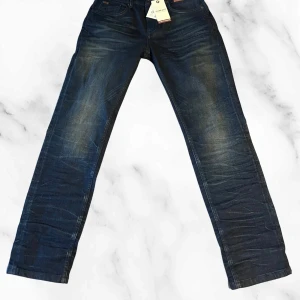 No Excess 711 Regular Fit jeans blå - Mörkblå jeans från No Excess, modell 711 Regular Fit. Klassisk femficksdesign med snygga slitningar och kontrastsömmar. Jeansen har en phone pocket och komfortabel passform. Perfekta för dig som gillar stilrena och bekväma jeans.