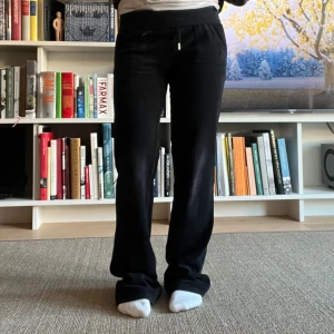 Svarta Juicy Couture byxor  - Svarta mjukisbyxor i mjukt material med raka ben och snörning i midjan. Byxorna har fickor fram och bak, samt en relaxed passform som ger en chill vibe. Perfekta för att hänga hemma eller när du vill vara bekväm men ändå se snygg ut.