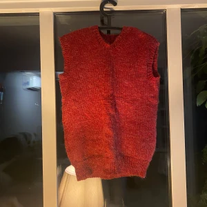 Röd stickad väst med v-ringning - Säljer en röd stickad väst med v-ringad hals. Mamma som har stickat den själv😊storlek S/M