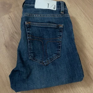 Mörkblå jeans från tiger of sweden - Snygga mörkblå jeans från tiger if sweden med klassisk femficksdesign och kontrastsömmar. Jeansen har raka ben och slim passform, sitter som slim, de e tillverkade i slitstarkt denimtyg. Perfekta för en avslappnad och stilren look. Väldigt feta jeans. Storlek 27/34, hör av dig vid fundering. Kan gå ner i pris vid snabbt köp!