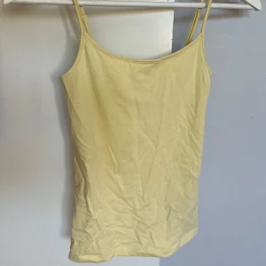Ljusgul linnetopp med smala axelband - Säljer ett enkel och fräscht ljusgult linne med smala axelband. Det är bekvämt och passar perfekt som man vill ha det, men har tyvärr inte kommit till användning för mig. Säljer även ett likadant i blått i xxs!