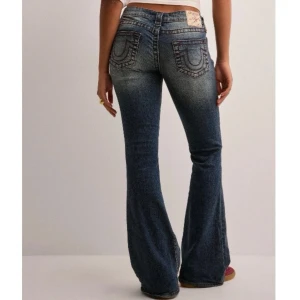 True Religion Ultra Low Rise Flare Jeans - Snygga blå bootcut jeans från True Religion med klassisk logga på bakfickan och markerade sömmar. Jeansen har låg midja och är tillverkade i jeansmaterial med lätt tvättad look. Dessa är använda två gånger och är som ny! 