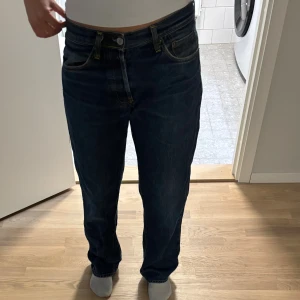 Evisu jeans - Blå Evisu jeans med raka ben och normal passform. Jeansen har tydliga röda broderade detaljer på bakfickorna och traditionell femficksdesign. Tillverkade i robust denim och har på baksidan en grej så man kan dra in midjan.