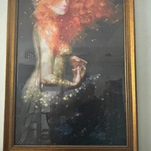 TAVLA MED GULD RAM SJÖJUNGFRU  - Tavla med fet guldram visar en inramad konstbild av en kvinna med långt, rött hår och fantasifullt uttryck.. mått 79CM X69CM STOR TAVLA .GLAS SKIVA 