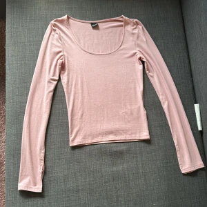 Ljusrosa långärmad topp Gina Tricot - Säljer en ljusrosa långärmad, kroppad topp från Gina Tricot. Toppen har en u-ringning vilket gör att toppen blir jätte fin. Det är ett mjukt stretchigt matrial. Ärmarna har en liten slits vid ärmslutet för extra detalj. Perfekt att styla med jeans eller kjol.