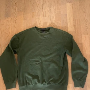 Grön sweatshirt från H&M Relaxed Fit - Mörkgrön sweatshirt från H&M i relaxed fit. Tröjan har rund halsringning, långa ärmar och ribbade muddar vid ärmslut och nederkant. Tillverkad i mjuk bomullsblandning, perfekt för en chill och avslappnad stil.