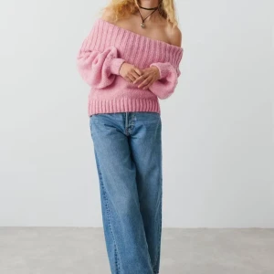 Rosa offshoulder stickad tröja - Supermysig rosa stickad tröja med bred ribbad kant och offshoulder-design. Tröjan har långärmade puffiga ärmar och är perfekt för dig som vill ha en chill och snygg look. Mjuk och fluffig känsla, passar till jeans eller kjol.