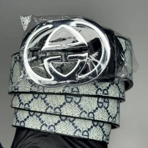 Gucci bälte med GG-spänne - Snyggt Gucci-bälte med klassiskt GG-mönster i blått på vit bakgrund och ett stort, silverfärgat GG-spänne. Bältet har en exklusiv vibe och är tillverkat i skinn med tydlig logga som sticker ut. Perfekt accessoar för att lyfta din outfit.